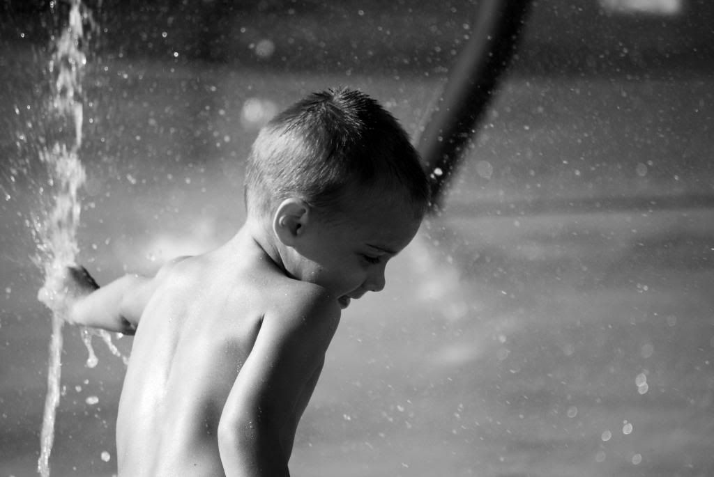 little boy in sprinkler black and white summer time fun